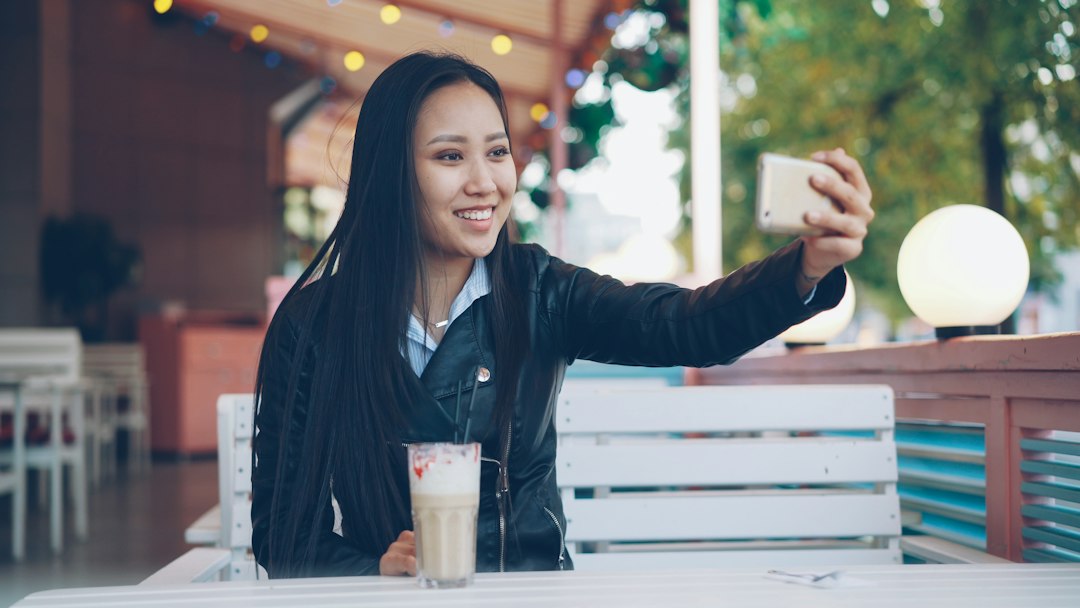 Creator chatting on a smartphone from a cafe; photo by Vitaly Gariev via Unsplash